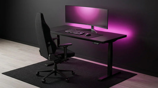 Black height-adjustable standing gaming desk with ergonomic chair — sit-stand ergonomic gaming desk setup